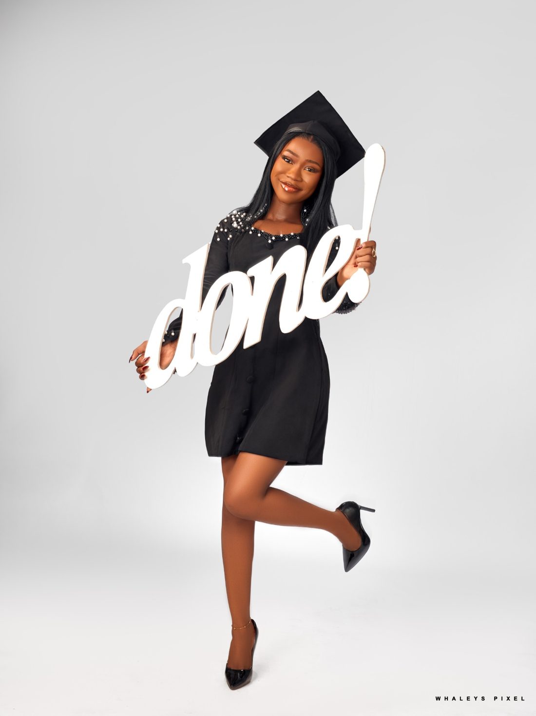 Victoria in a graduation cap holding a sign that says done